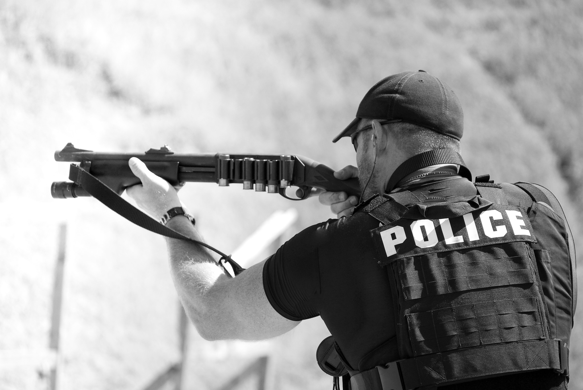 A police officer aiming a Remington 870 shotgun, black and white photo