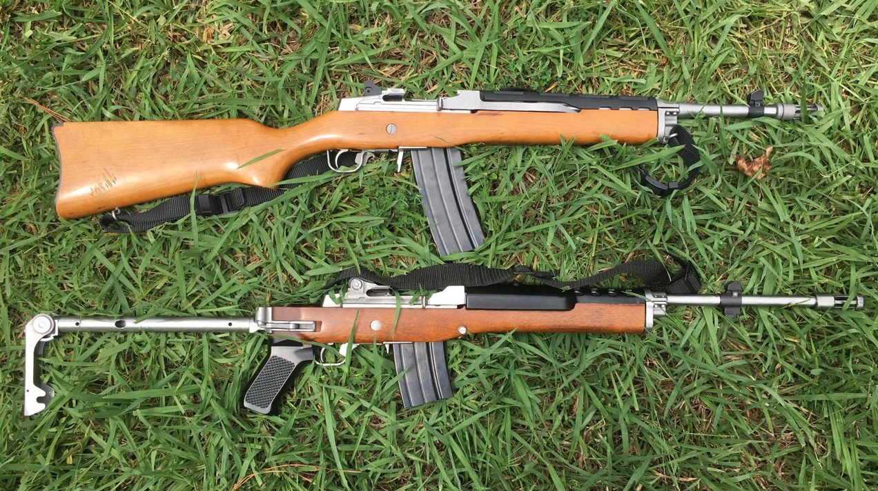 Two Ruger Mini-14 rifles in the grass, one with a fixed wood stock and one with a folding stock